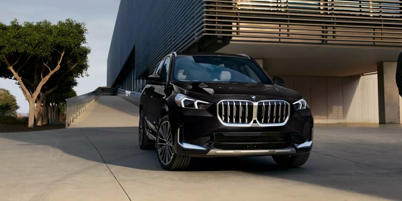 Black BMW SUV driving on a scenic mountain highway with rocky landscape surroundings