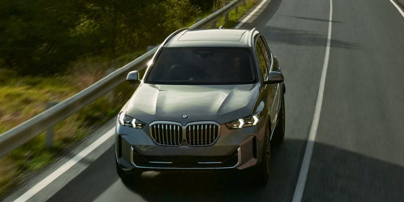 Front three-quarter view of a BMW crossover SUV parked outside a modern building, showcasing its distinctive grille